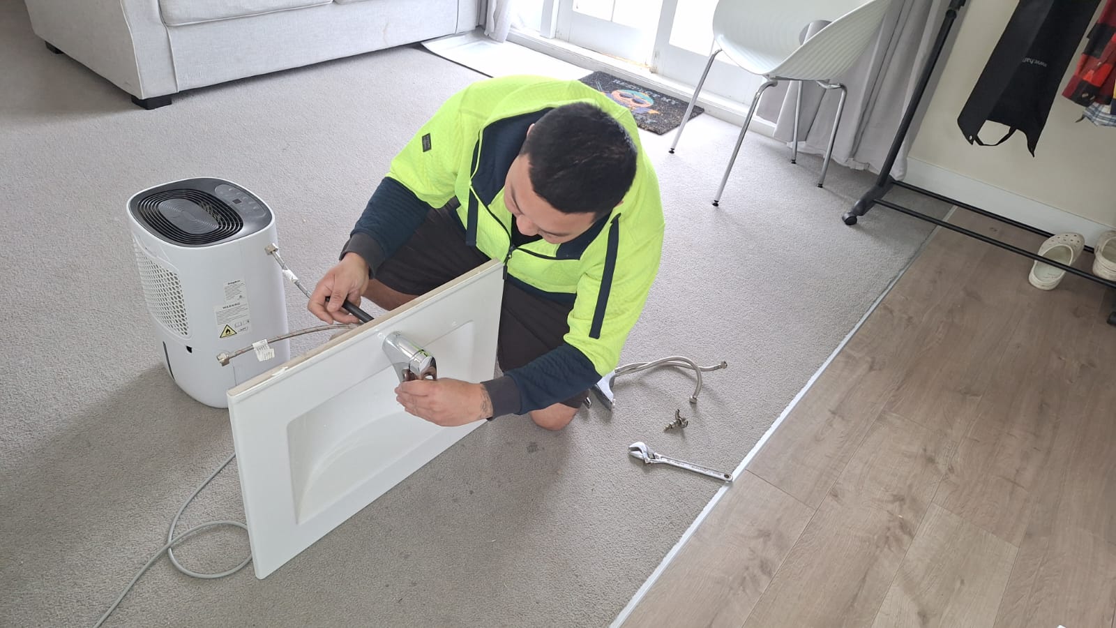 TradePlus handyman fitting new tapware to a bathroom vanity top in an Auckland home